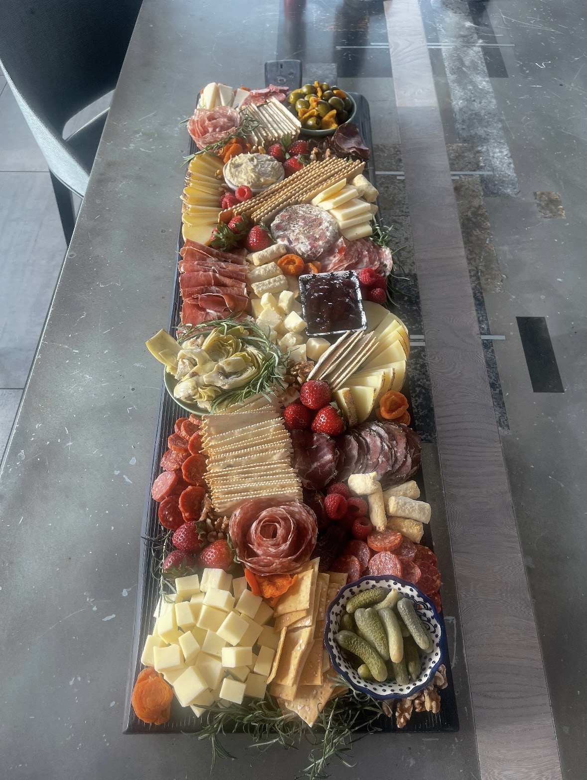 Long styled grazing table for a party with salami, aged cheeses, strawberries and cornichons — grazing table catering Anchorage AK